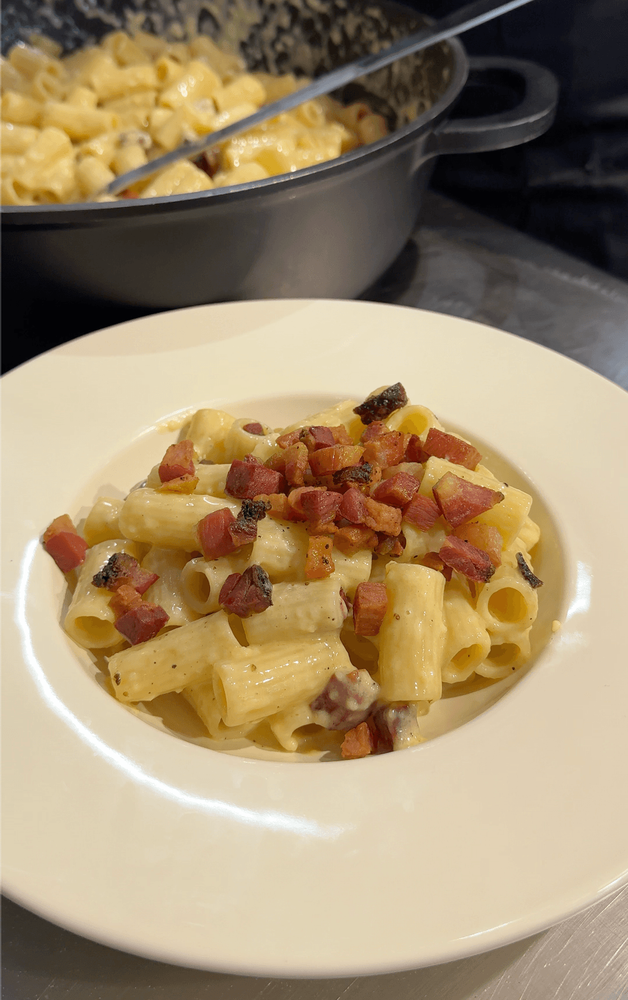 Assiette de Carbonara avec des Rigatoni al dente et du guanciale croustillant