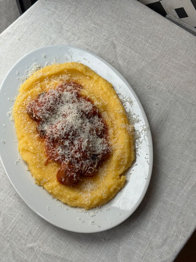 assiette de boulette de viande à la sauce tomate sur de la polenta crémeuse avec du parmesan râpé au dessus 