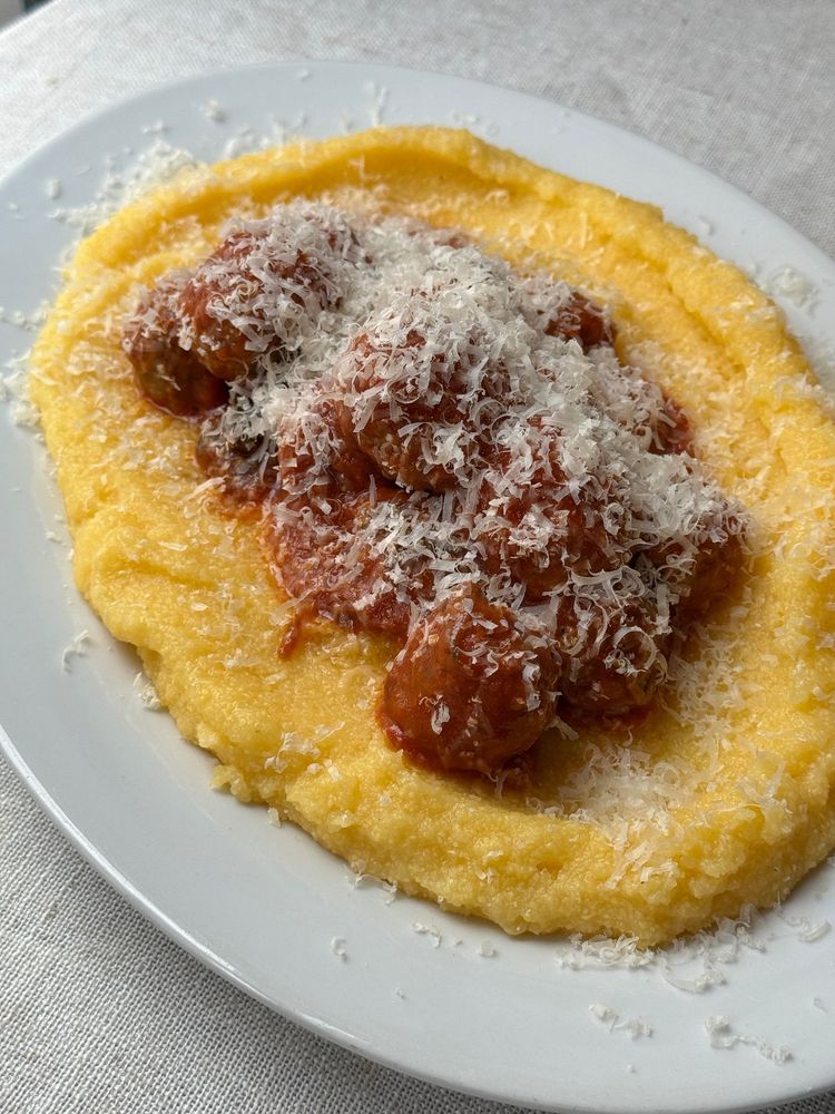 zoom assiette de boulette de viande à la sauce tomate sur de la polenta crémeuse avec du parmesan râpé au dessus 
