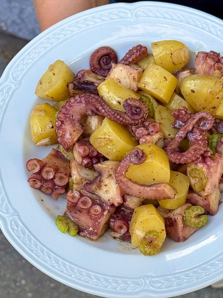 salade de poulpe, pomme de terre, céleri et oignon dressé dans une assiette blanche