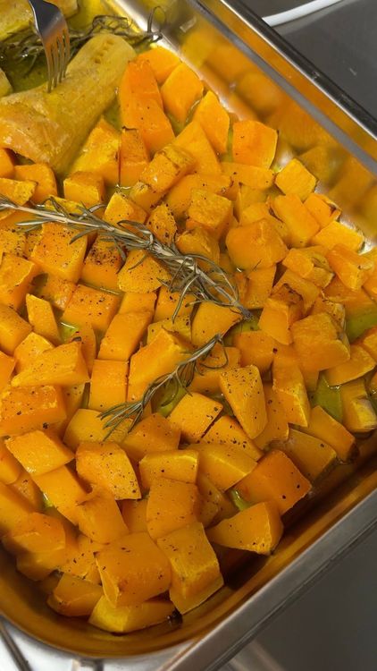 courge coupée en cube pour aller au four avec une branche de romarin fraîche