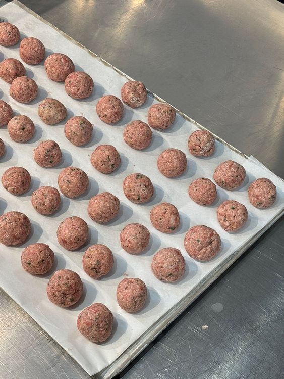boulettes de viande façonnées et alignées sur une plaque