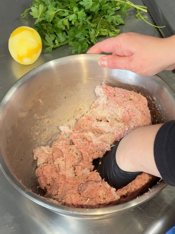 mélange manuel dans un saladier des viandes pour faire des boulettes